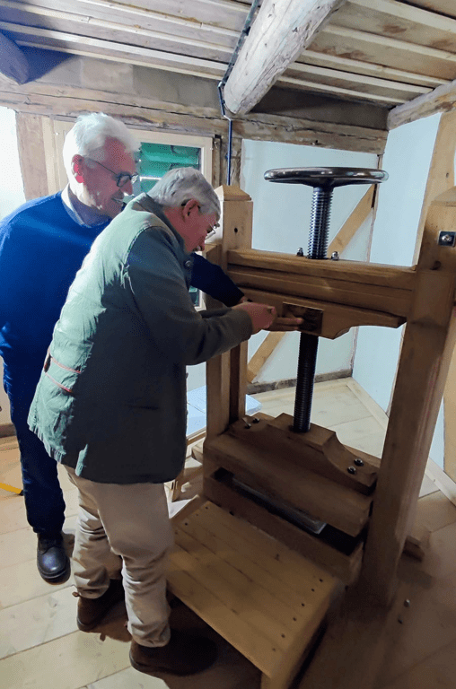 Der Vorstitzende des Fördervereins der Mühle Liesebach Klaus Röhr zeigt die neue Presse en Detail. Die erste Drehung ist immer die schwierigste