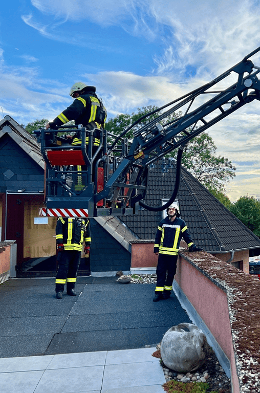 Die Feuerwehrleute kommen mit Drehleiter undSchleifkorb über die Dachterrrasse