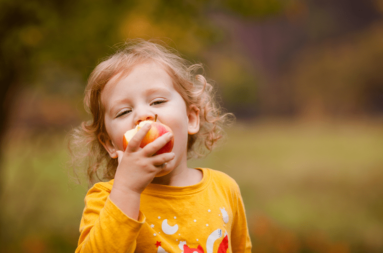 Kind beißt in einen Apfel