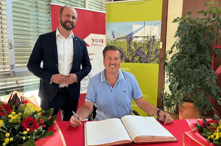 FSV Trainer unterschreibt in das Goldene Buch der Stadt Schöningen. Bürgermeister Malte Schneider hinter ihm